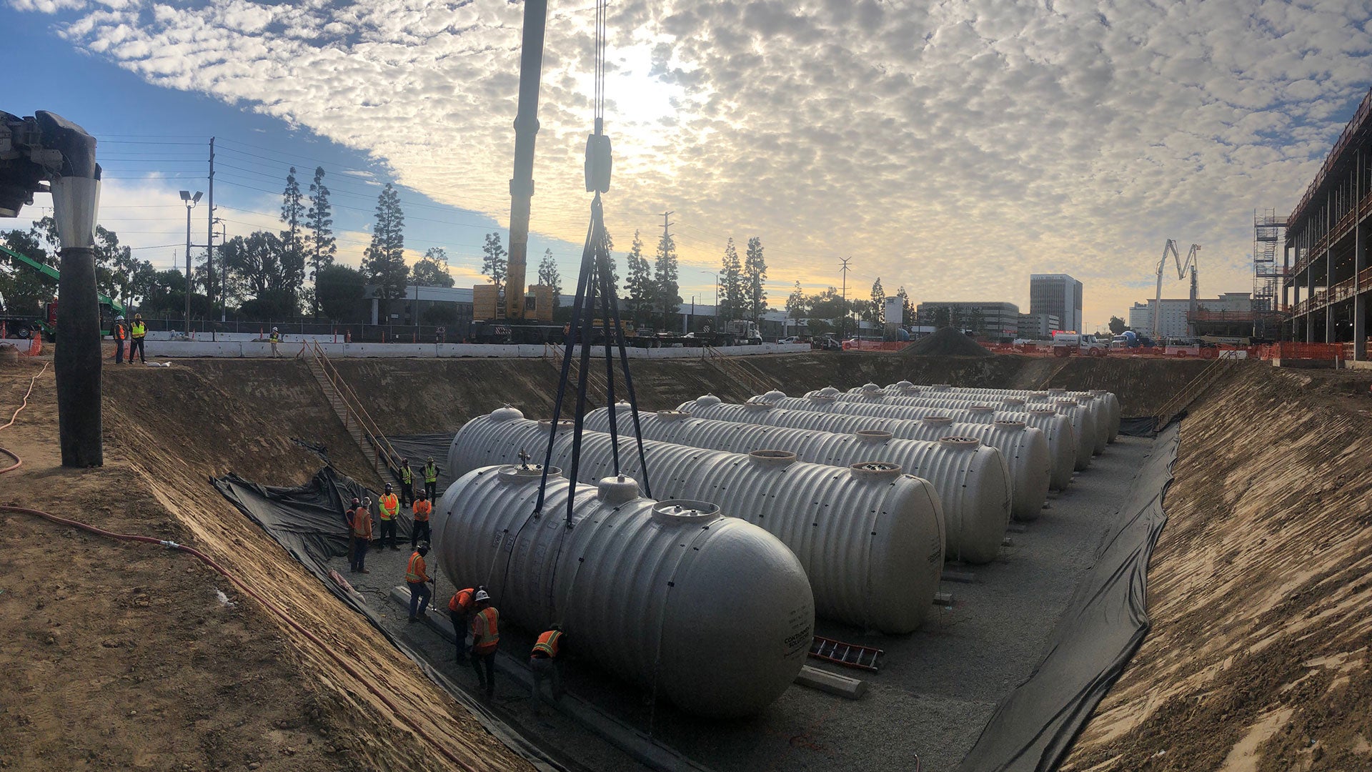 Wide shot of a row of steel tanks being installed underground
