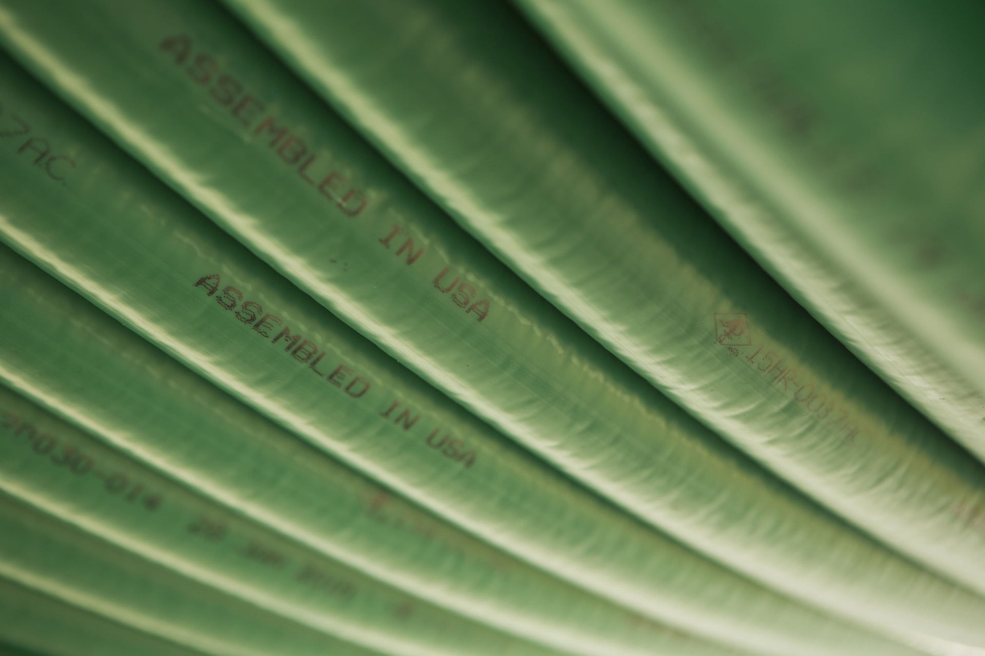 Closeup of green coiled tubing with printed text that says "Assembled in USA"