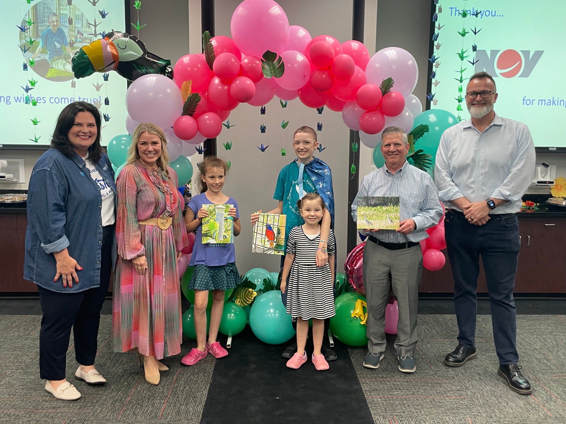 Group photo of Make-A-Wish recepient with balloon archway at NOV offices