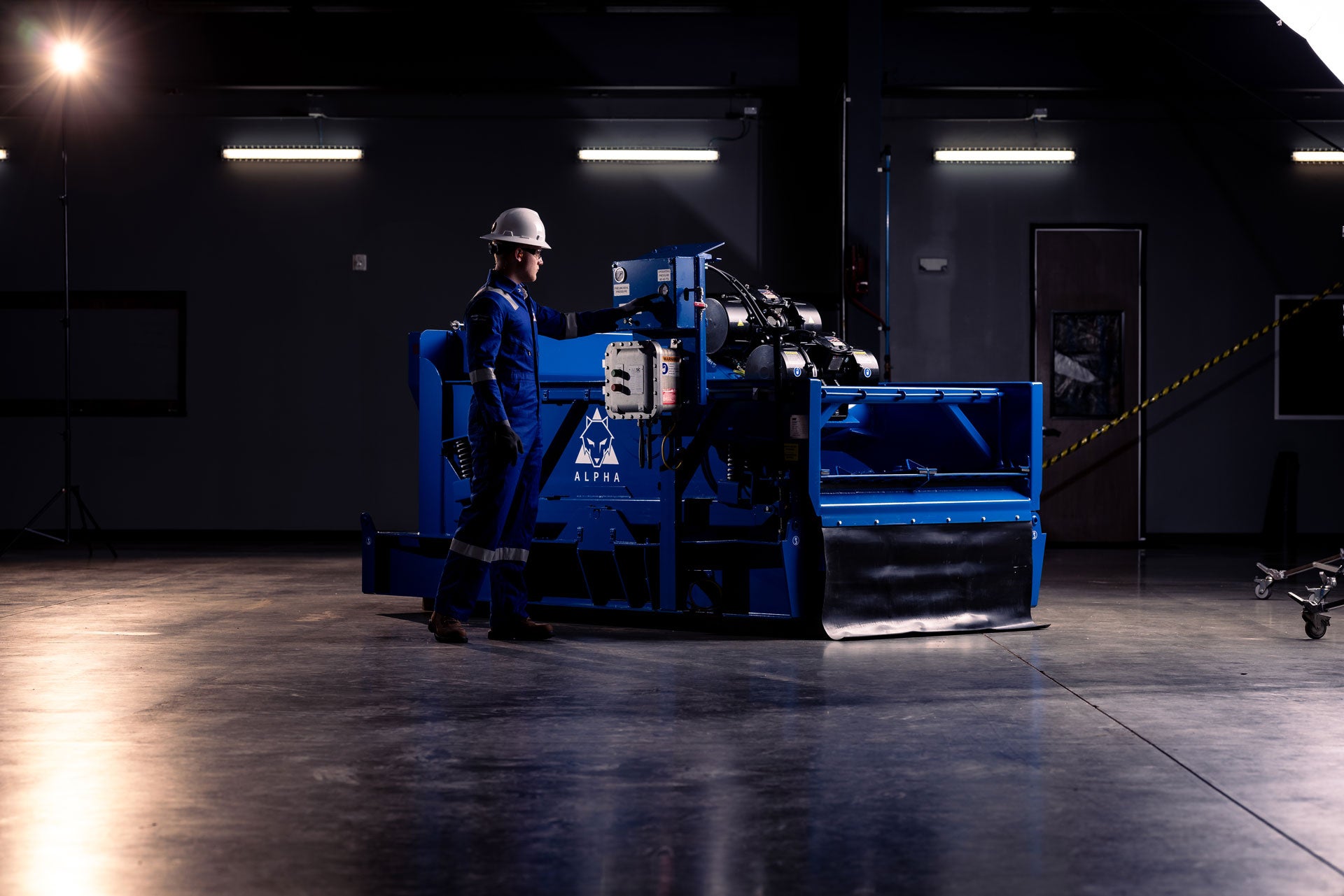 Technician wearing PPEs inspecting an Alpha Shaker in a facility