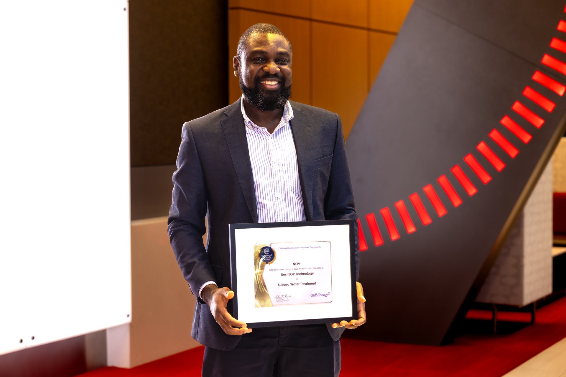 Samuel holding a framed Gulf Energy Excellence Award 2026