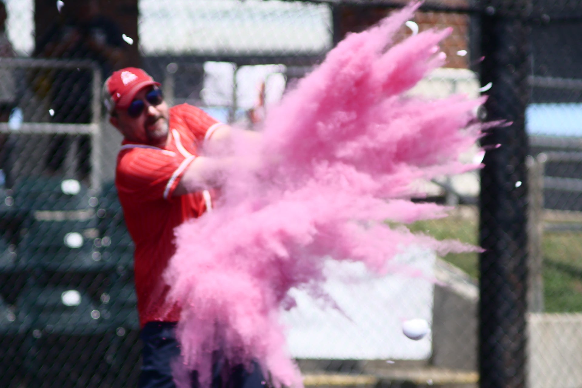 Man at bat hitting an exploding baseball with pink dust flying everywhere