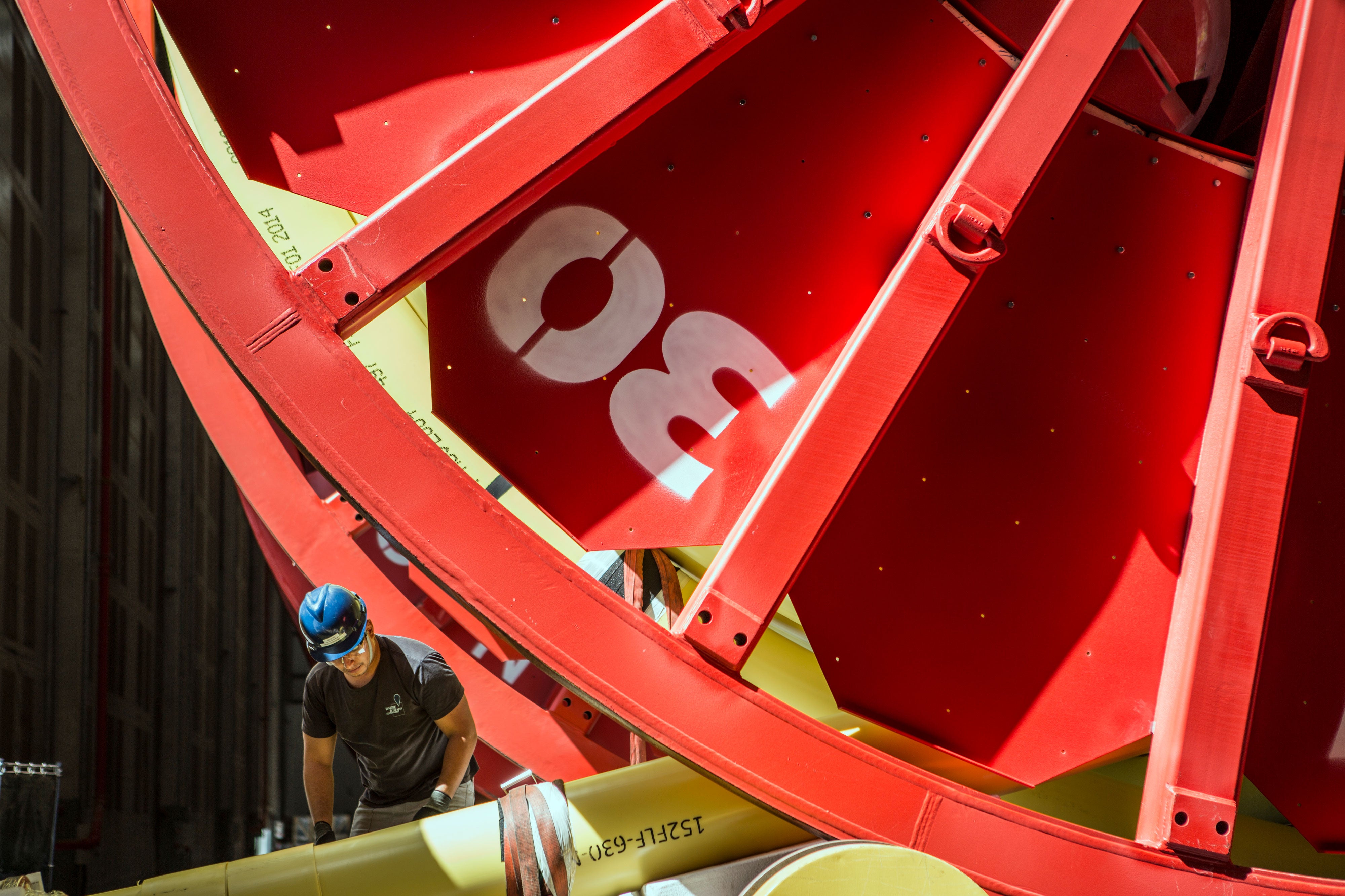 NOV employee working on large, red subsea equipment and yellow piping