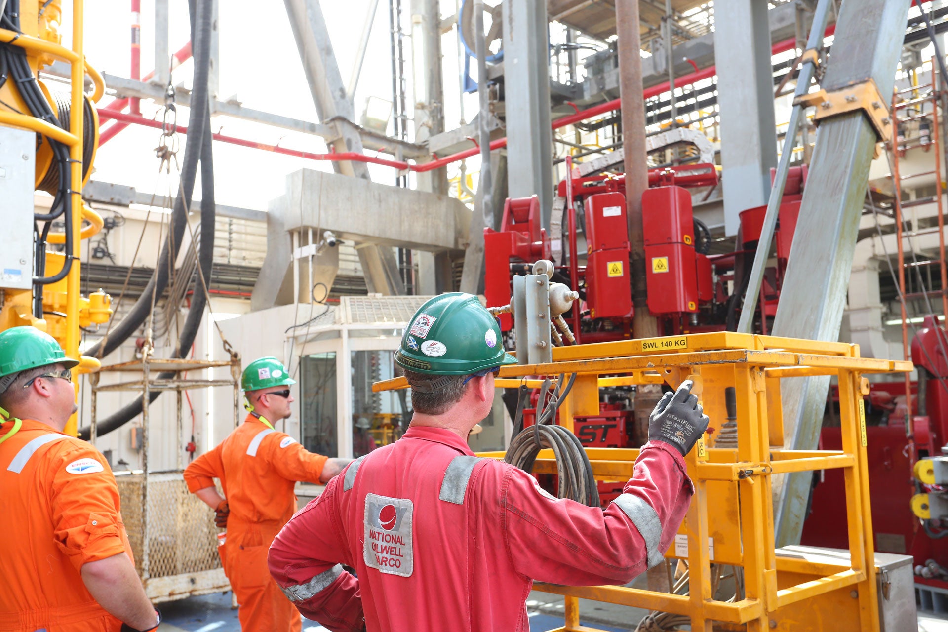 Three NOV technicians wearing PPE inspecting an iron roughneck