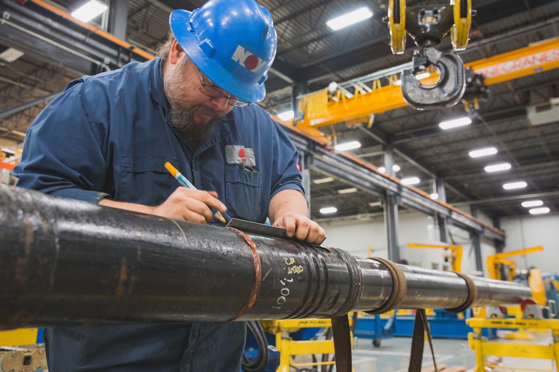 An NOV employee measures a pieces of tubing equipment